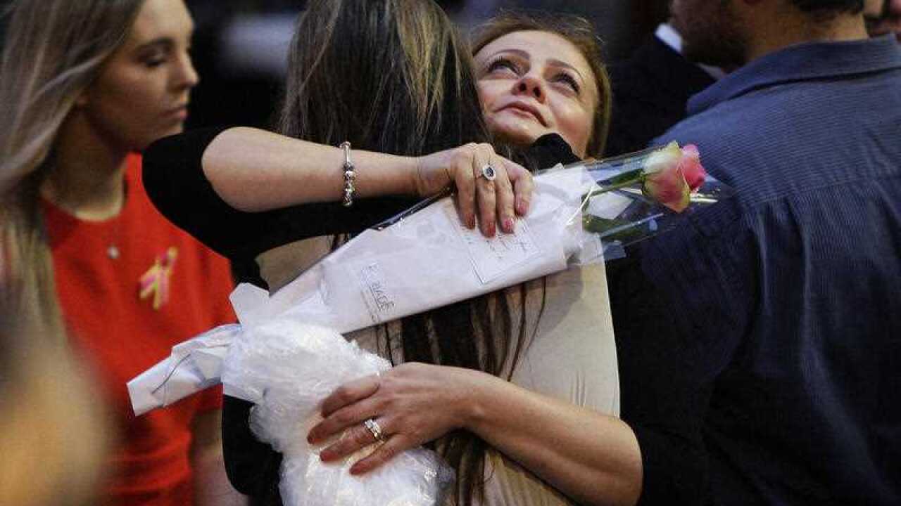 Lindt Cafe siege survivor Marcia Mikhael is embraced during a memorial service marking the first anniversary of Lindt Cafe Siege