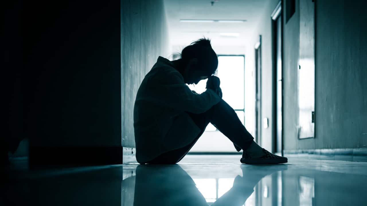 image of women with head in hands in empty dark corridor