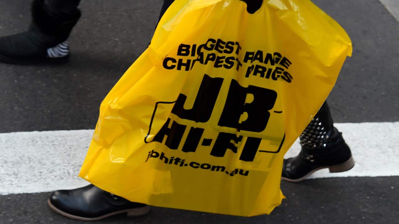A patron leaves a JB Hi-Fi store with a purchase in Sydney