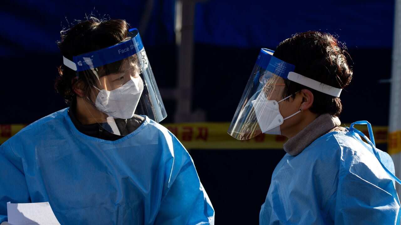 Health workers at a makeshift clinic testing for COVID-19 at Seoul Station in Seoul, South Korea, 14 December 2020.