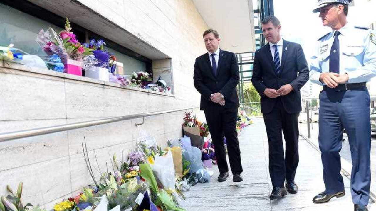 Police Minister Troy Grant, look at flowers placed for police employee Curtis Cheng outside of the NSW Police Headquarters in Sydney