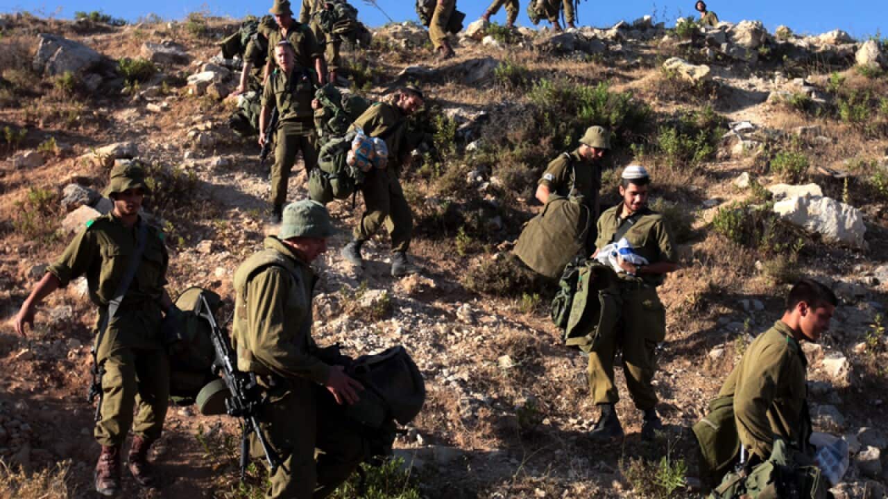 Israeli soldiers climb down a steep hill during a search mission
