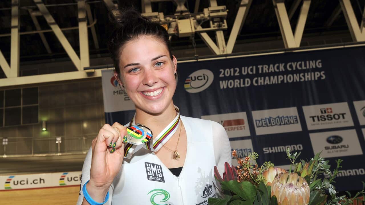 A woman shows her medal after competing in a cycling race.