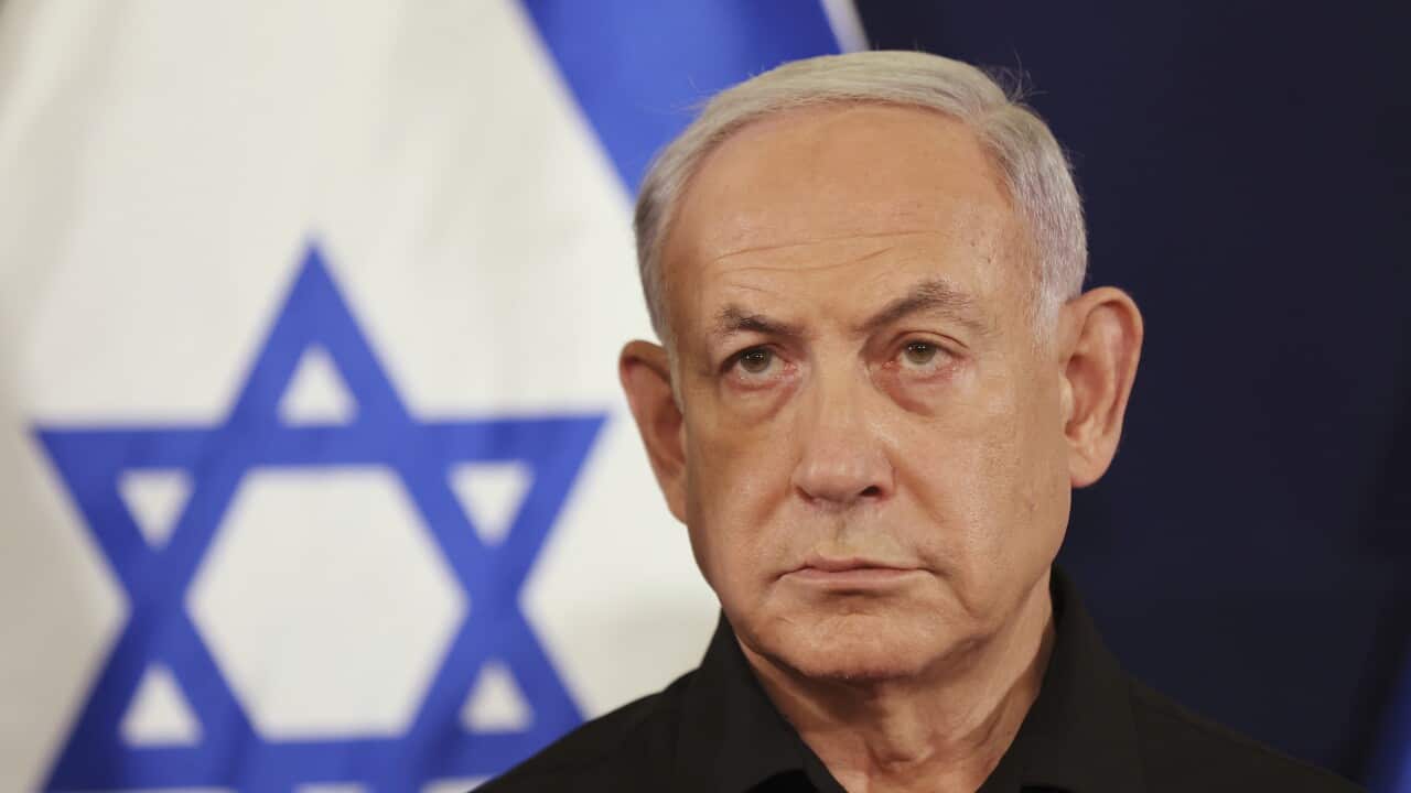 Benjamin Netanyahu wearing a black shirt. The Israel flag is in the background