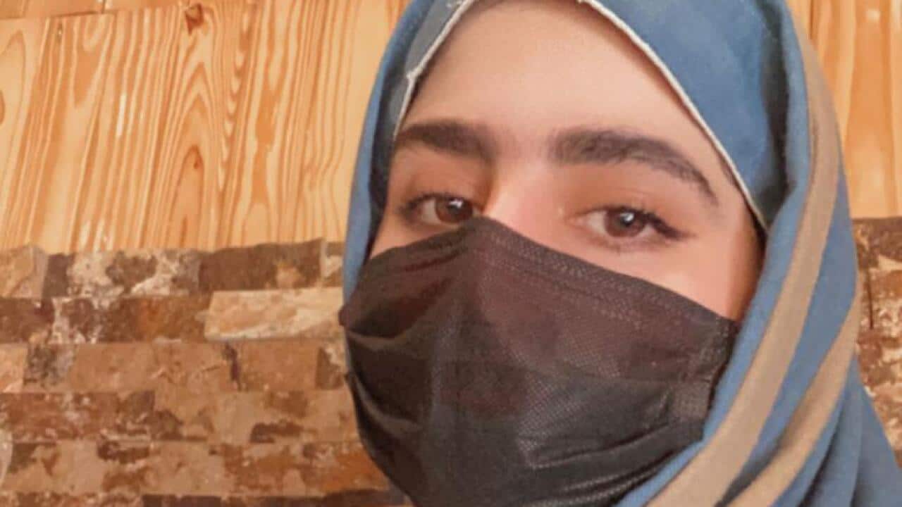 Woman in blue hijab and black mask.