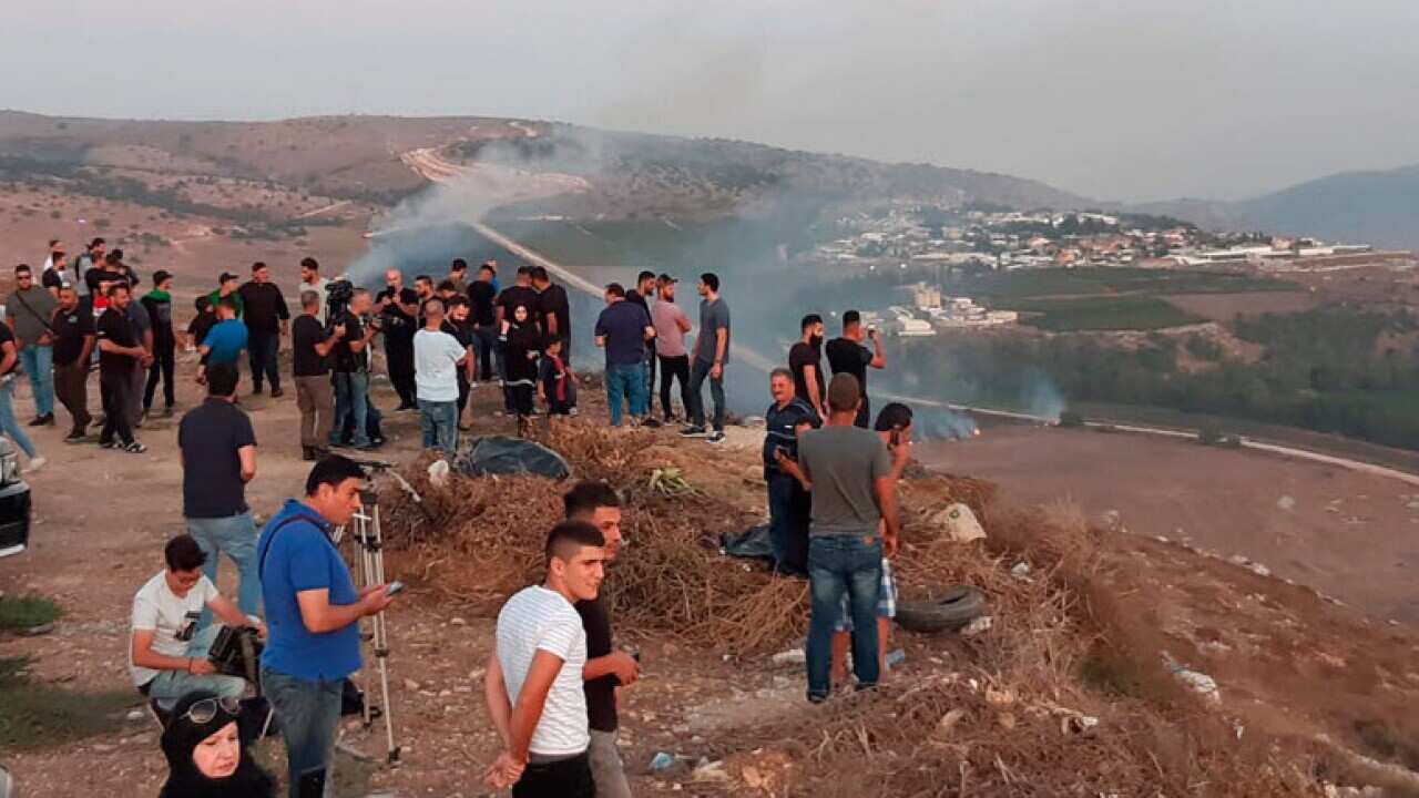 Lebanese journalists and villagers watch as Israeli army shells cause fires on the southern Lebanese border village of Maroun Al-Ras.