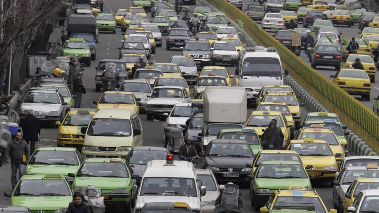 Cars drive in a congested traffic in a central square of Tehran