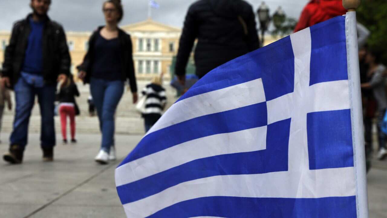 A Greek flag as pedestrians walk at the main Athens' Syntagma square