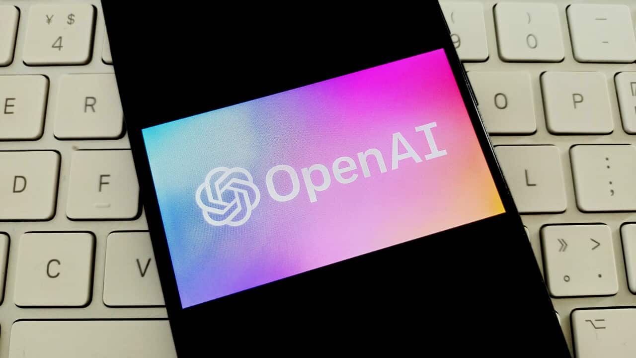 Mobile phone on a computer keyboard with OpenAi logo on the screen.