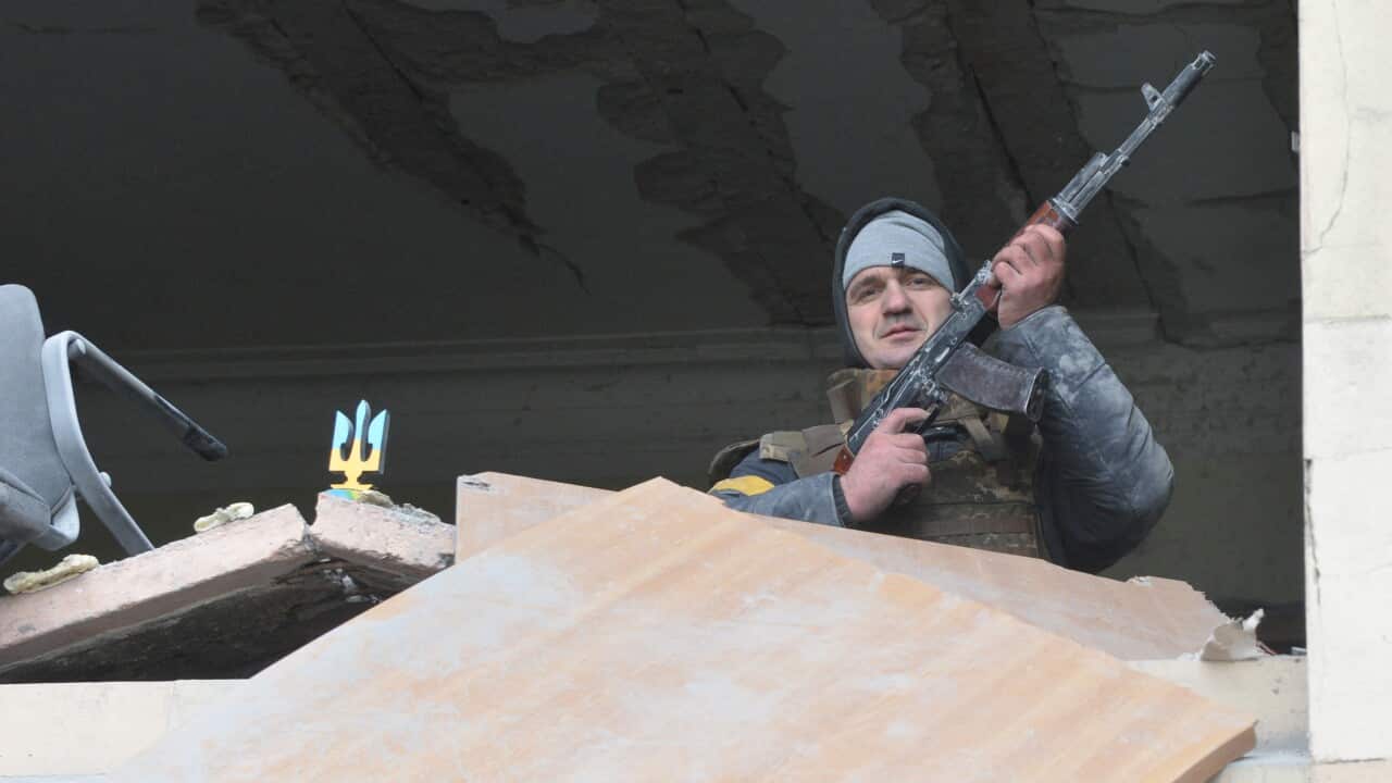 An armed man is seen inside the damaged local city hall of Kharkiv, destroyed as a result of Russian troop shelling.