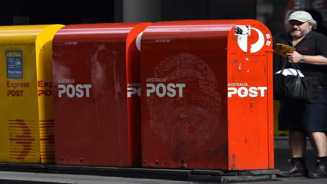 A man posting a parcel at an Australia Post box