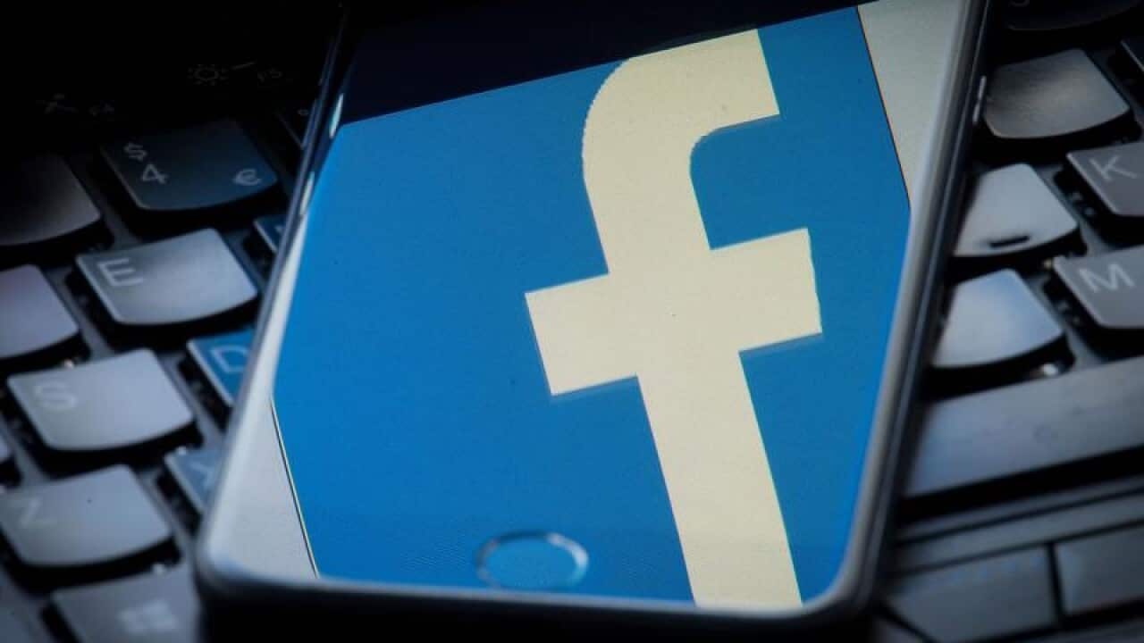 A Facebook logo is reflected on a phone screen.