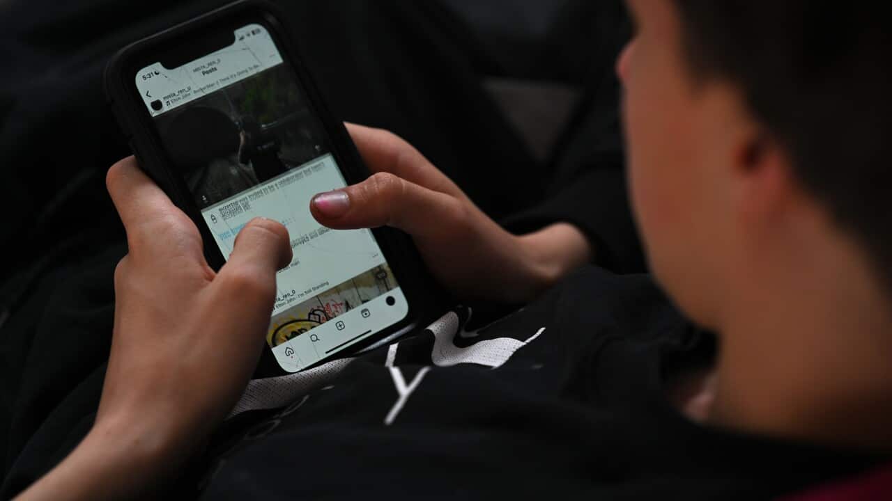 A teenager looking at a social media site on a mobile phone.