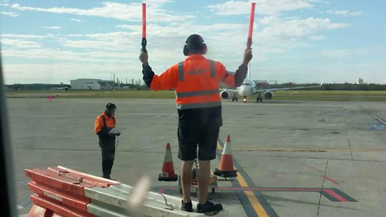TWU picture shows an Aerocare worker standing on bollards to direct a plane.