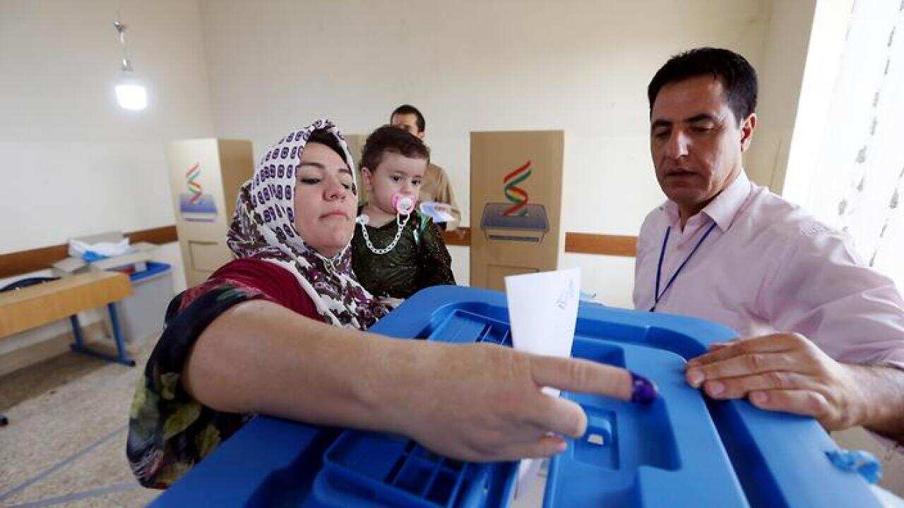 An Iraqi Kurd woman picks up ballot paper before casting her vote at a polling station during Kurdistan independence referendum in Erbil