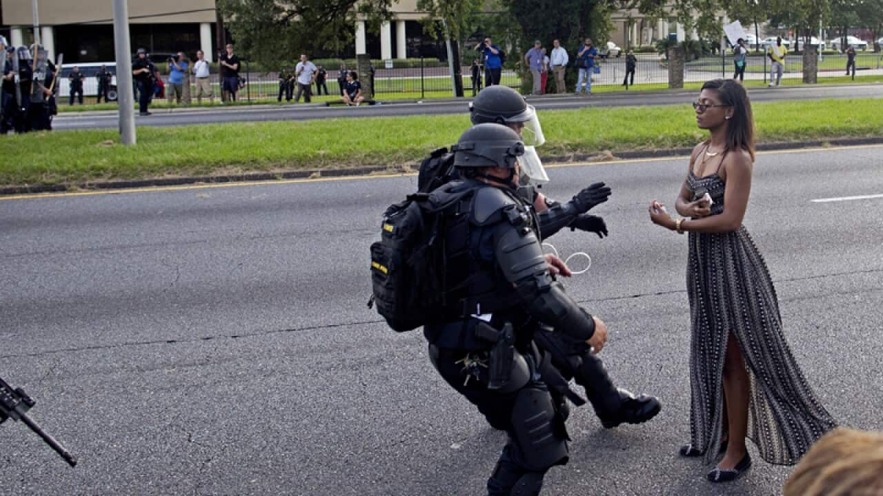 A protester is grabbed by police officers in riot gear