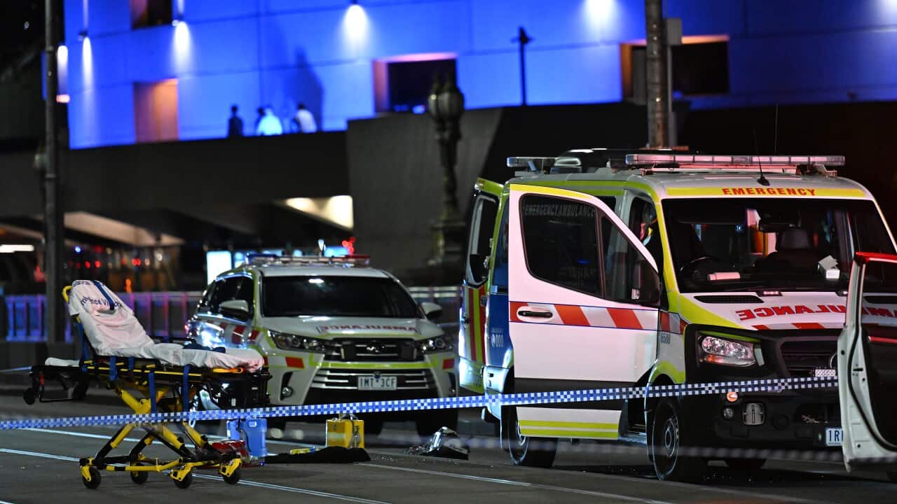 Police tape in front of an ambulance pulled over, with an empty stetcher bed next to it.