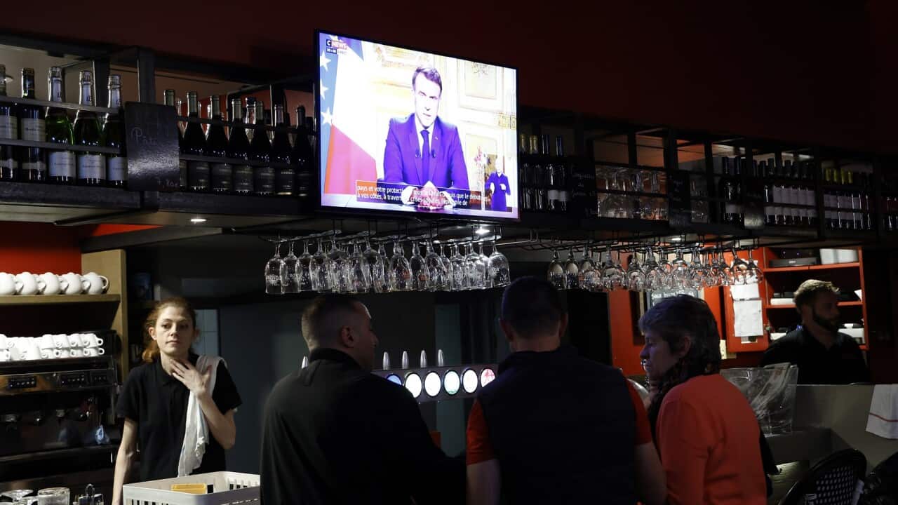 People in a bar in SW France listen as President Macron speaks of the government's collapse (AAP)