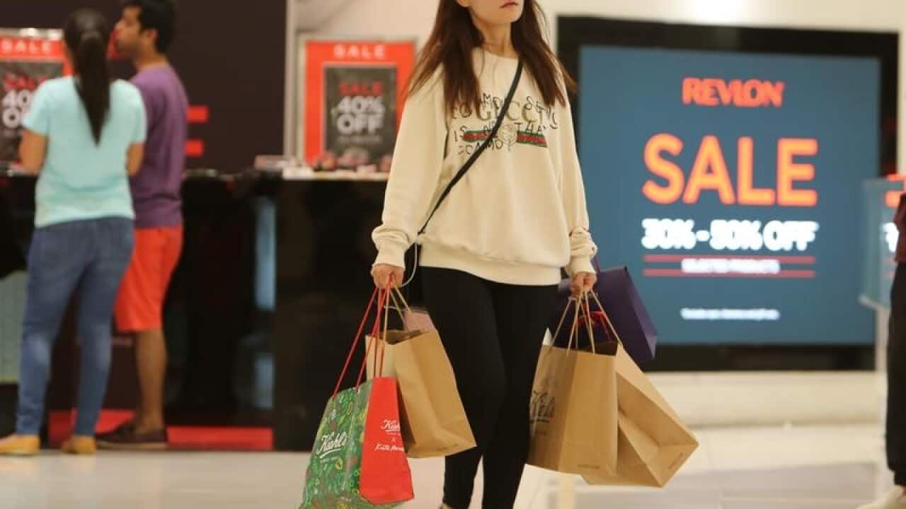 A shopper carries bags through a department store.