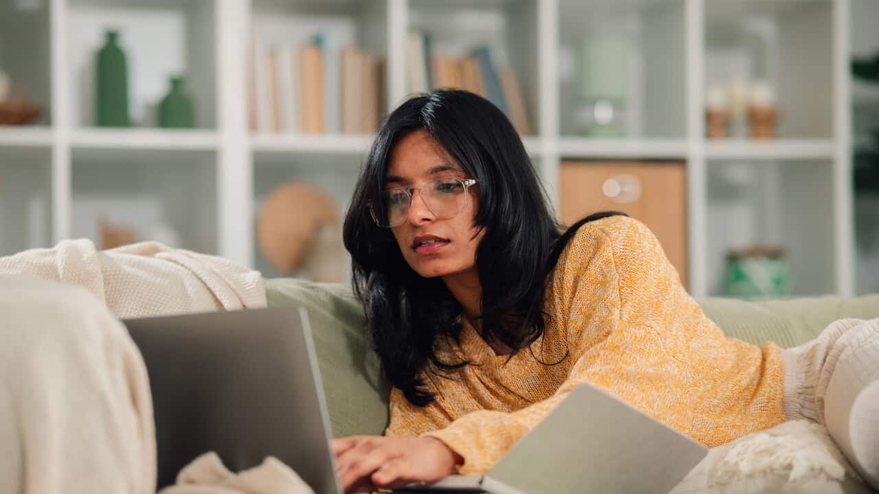 Young woman studying at home, working remotely on laptop, enjoying comfortable flexible work life