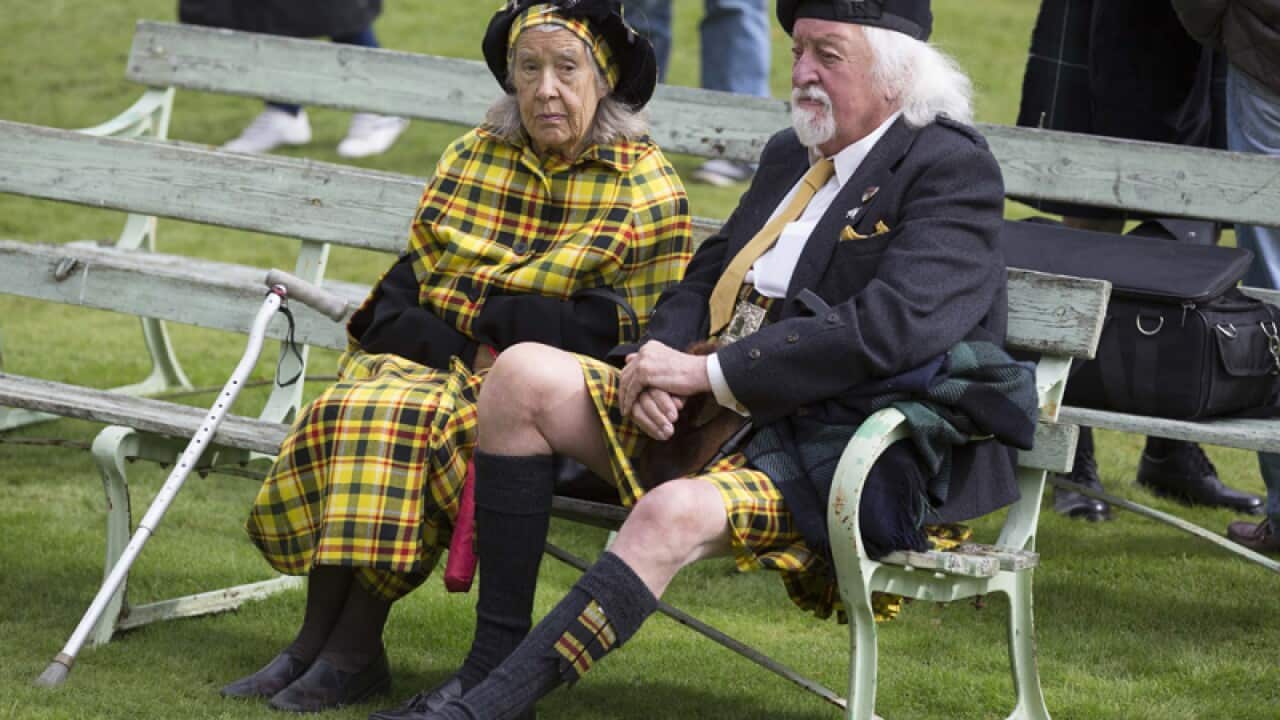 A Scottish couple listen to the bagpipe competition