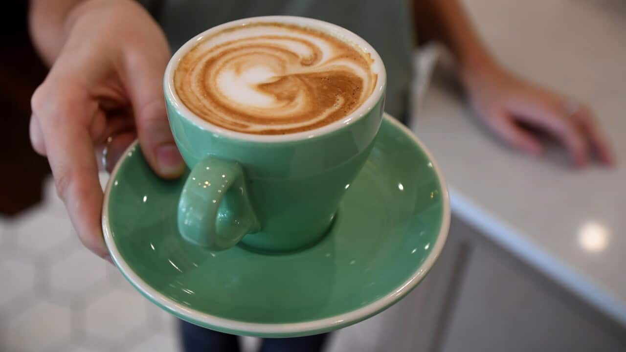A waitress is seen holding a coffee at a cafe in Canberra, Thursday, Feb. 23, 2017. The Fair Work Commission today announced cuts to Sunday and public holiday penalty rated in the retail and hospitality industries. (AAP Image/Lukas Coch) NO ARCHIVING
