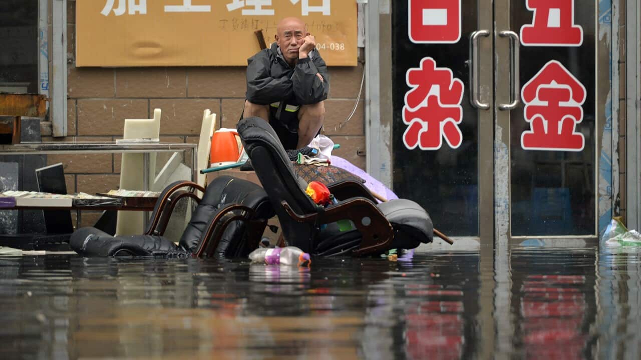In this Thursday, July 21, 2016 photo, a man sits outside of a flooded shop in Shenyang in northeastern China's Liaoning Province.