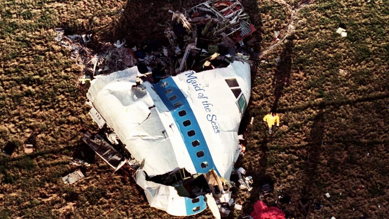 Investigators look at what remains of the nose of Pan Am 103 in a field in Lockerbie in 1988