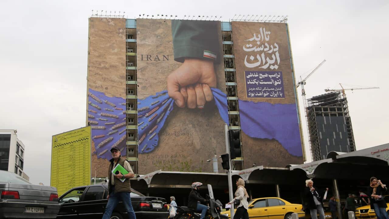 A large billboard on the side of a building showing a hand reaching down and lifting a stylised body of water with ships on it