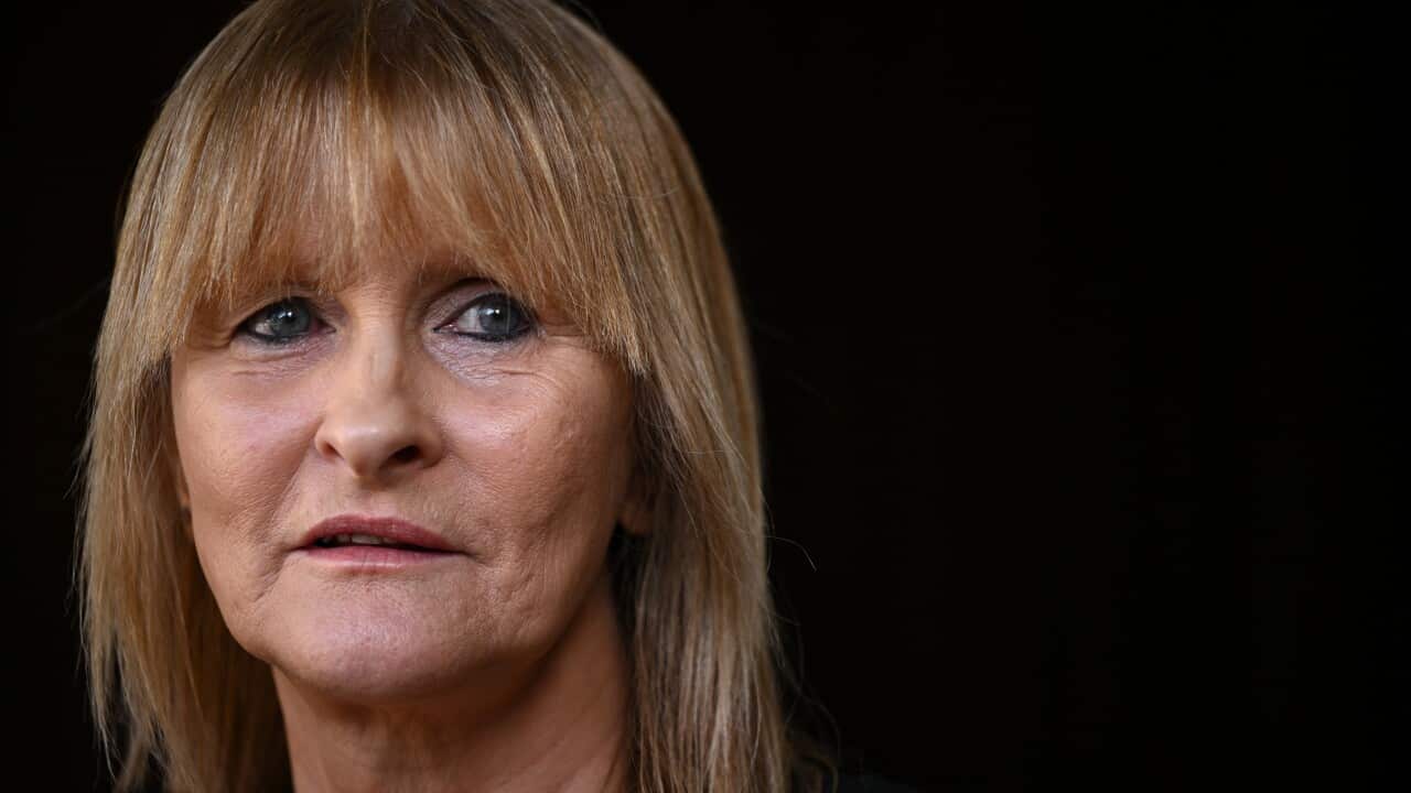 a middle aged blonde woman with a black background