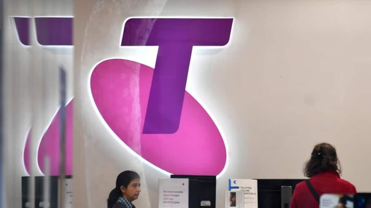 Customers and assistants are seen in a Telstra store in Sydney.