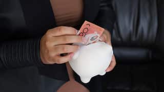 Someone putting money into a piggybank.
