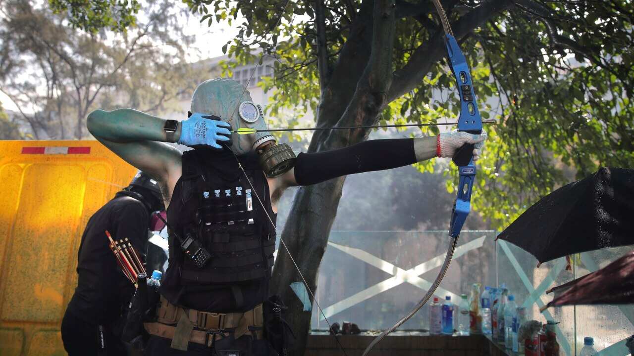 A protestor prepares to fire a bow and arrow during a confrontation with police at the Hong Kong Polytechnic University