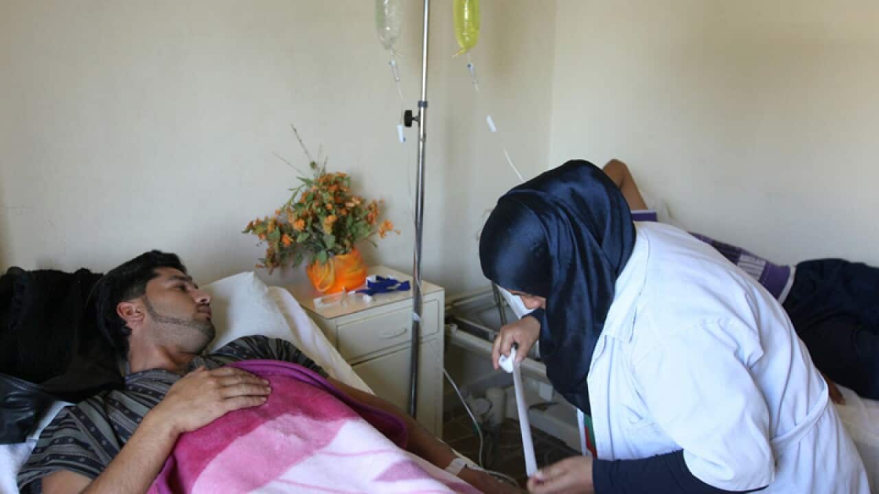 A Lebanese nurse, right, treats a Syrian man.