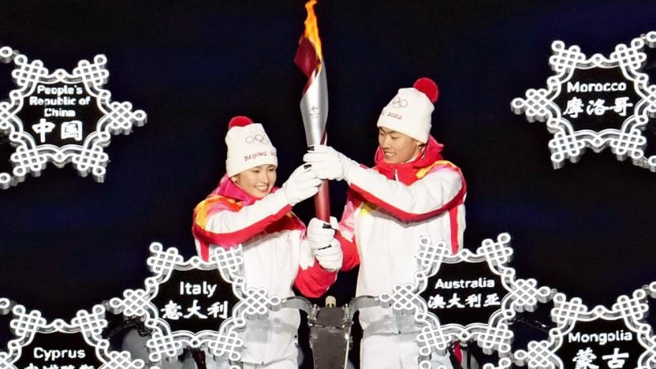 Dinigeer Yilamujiang and Zhao Jiawen hold the torch during the Winter Olympics opening ceremony.