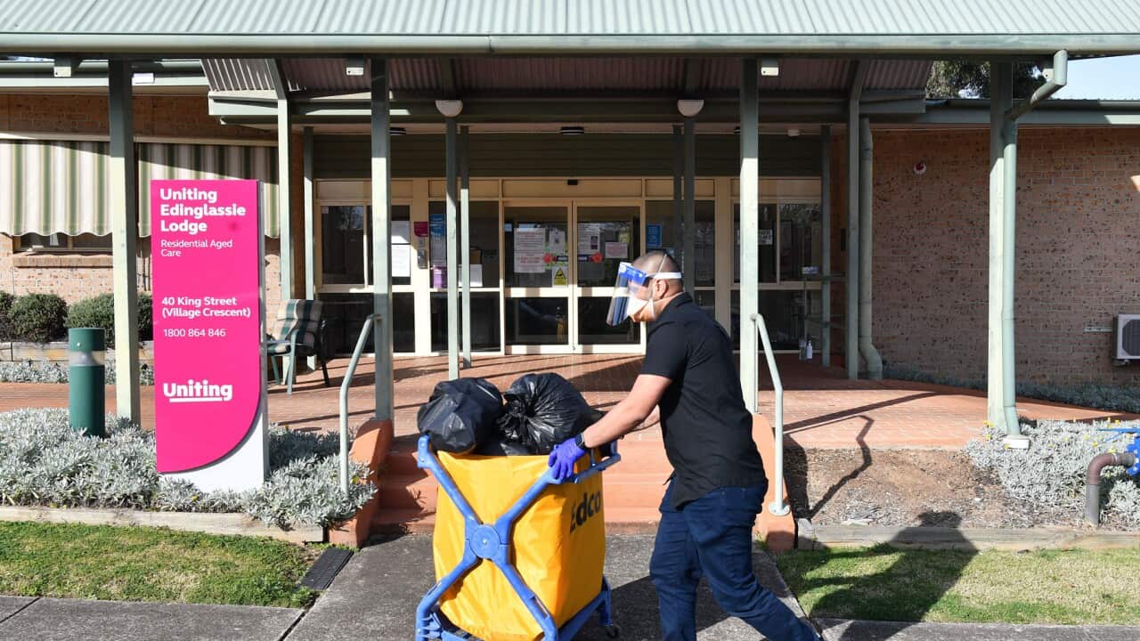 A cleaner wheels a trolley past an aged care lodge