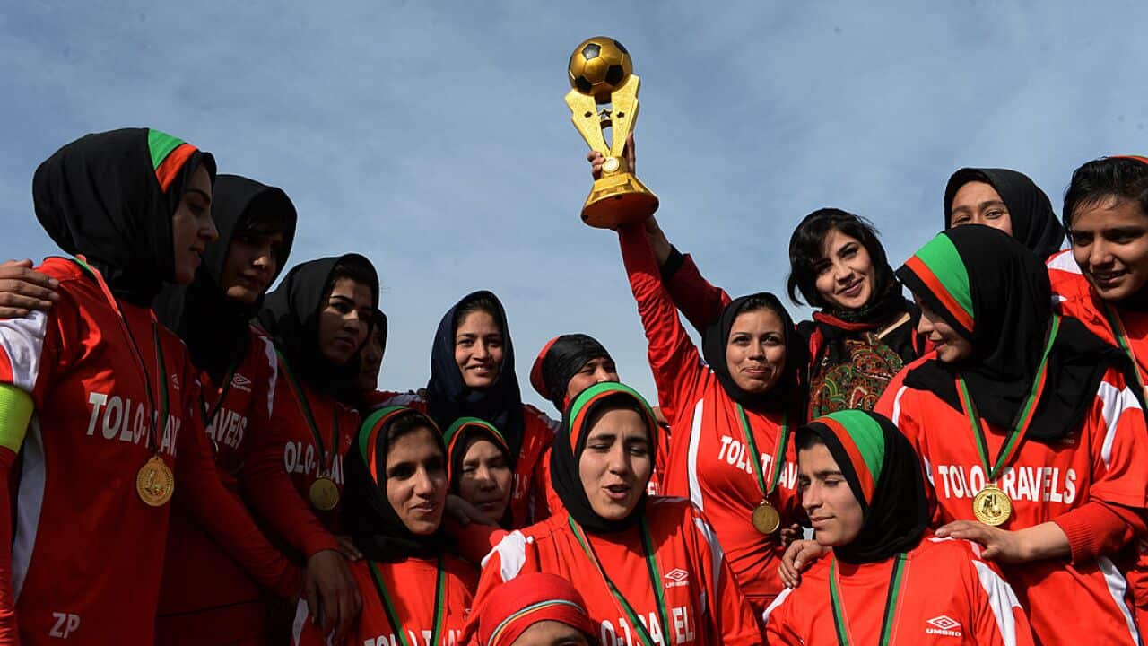 Afghan female football players celebrate with the trophy after their women's football tournament final match against Isteghlal in 2013.