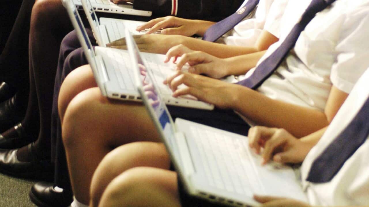 High school students work on laptop computers
