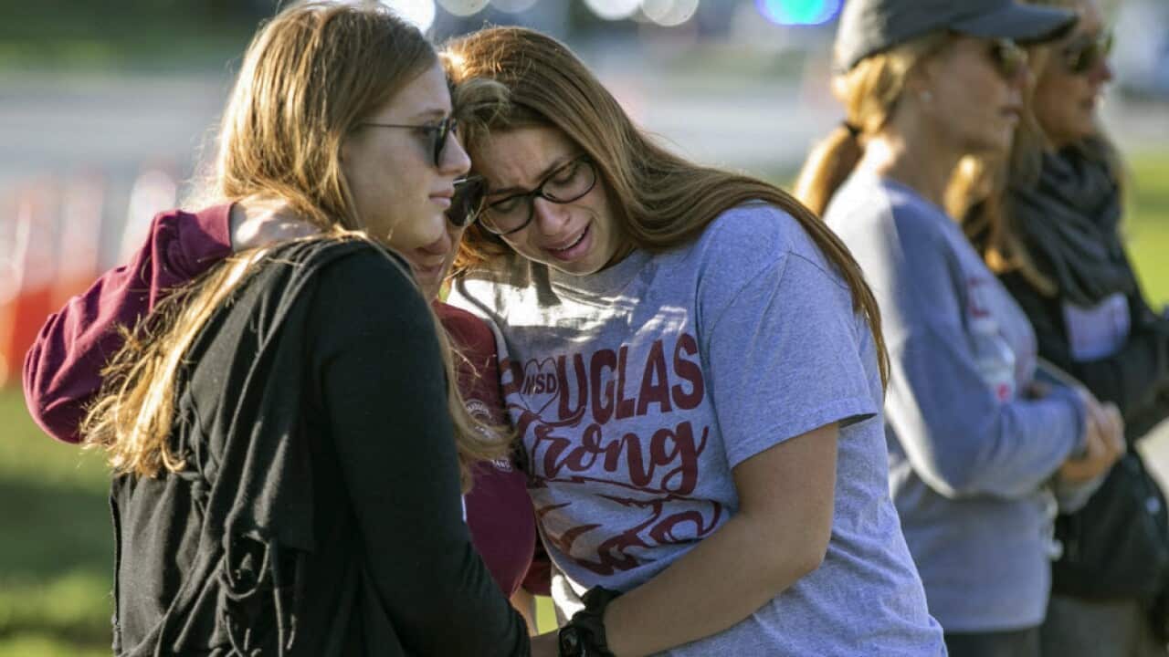People embrace at a memorial marking the one-year anniversary of a mass shooting at the school in Parkland, Florida.
