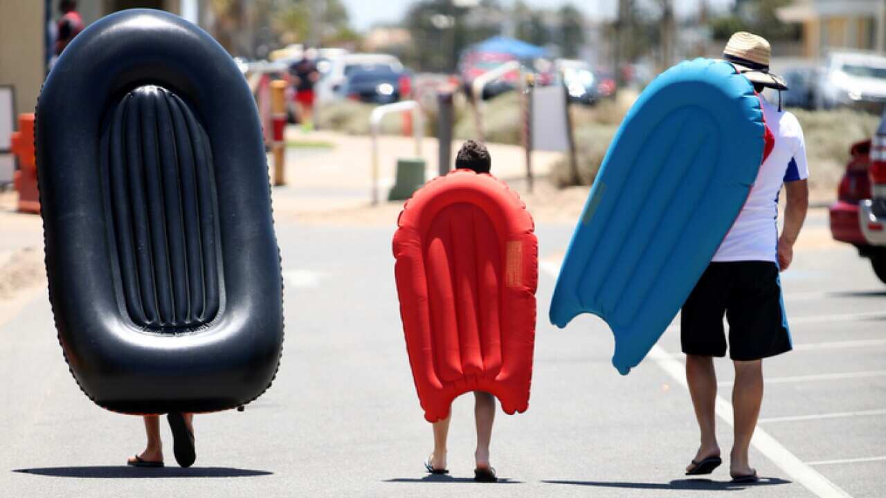 Beach goers cart their inflatable boats to West Beach during a hot day in Adelaide, Thursday, January 3, 2019. Temperatures soared across South Australia today, climbing close to 50C in some regional towns. (AAP Image/Kelly Barnes) NO ARCHIVING