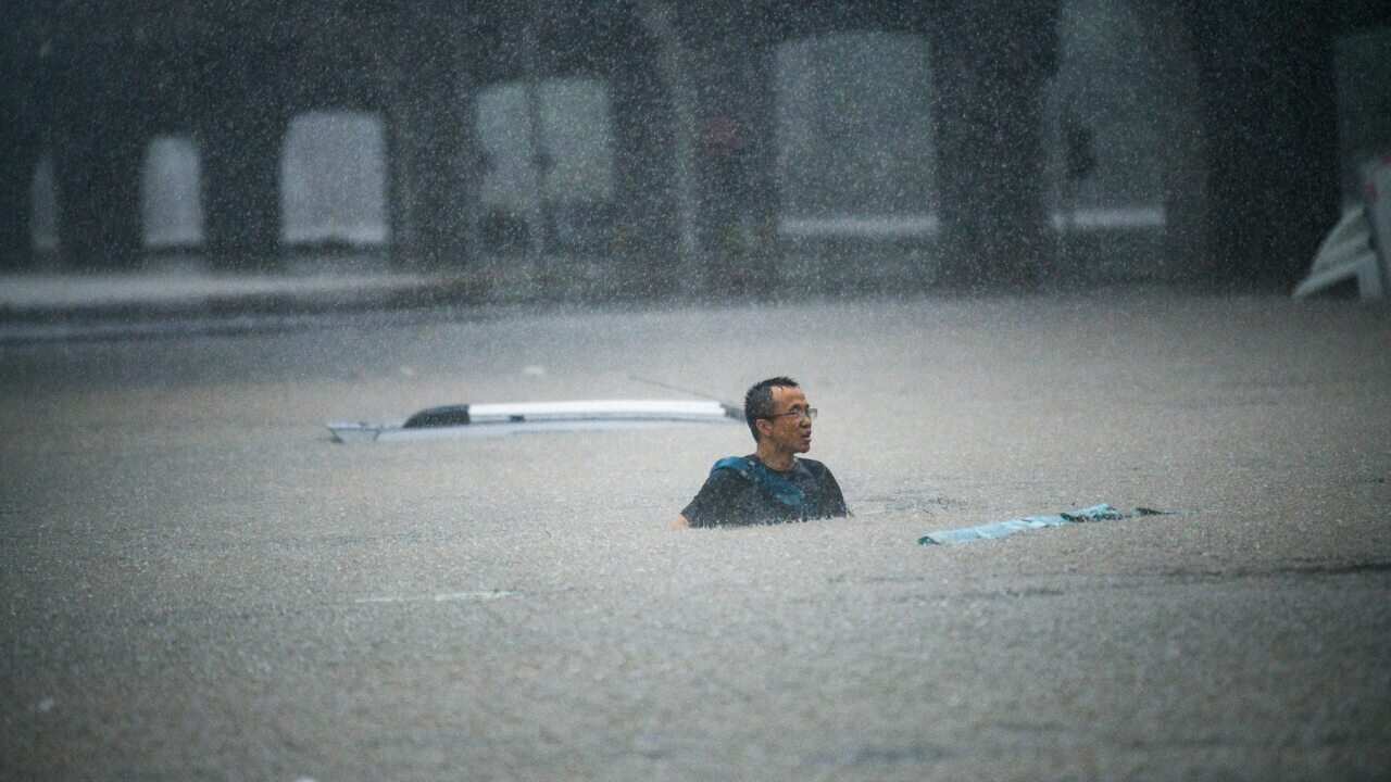 A person tries to swim across floodwaters caused by torrential rain in Zhengzhou, China, on 20 July 2021.