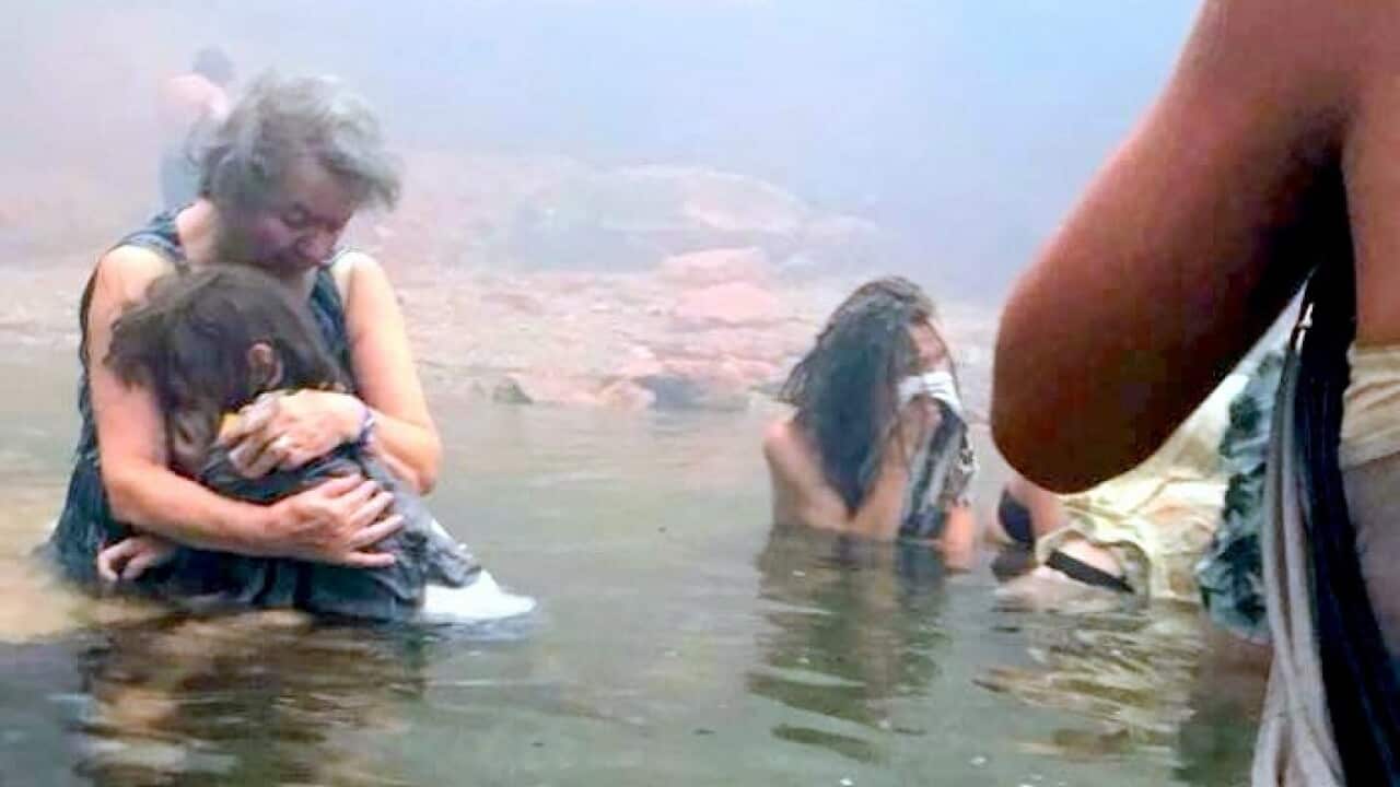 In this Monday, July 23, 2018 image from video provided by Elia Kallia, people escaping wildfires wade into the waters of the "Silver Coast" beach, Mati, Greece