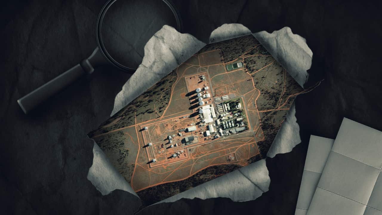 Satellite view of a facility in a remote area, with a ripped paper effect and magnifying glass behind it.