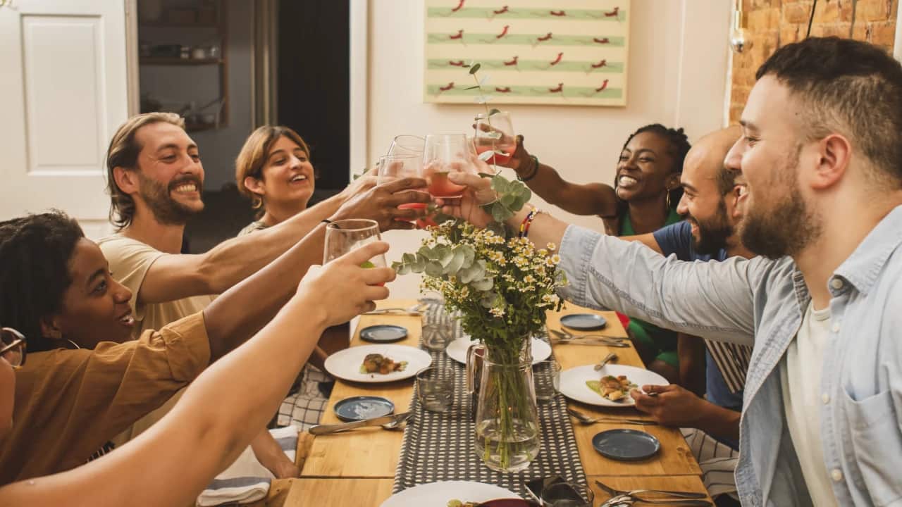Group of people raising their glasses in a social dining setting