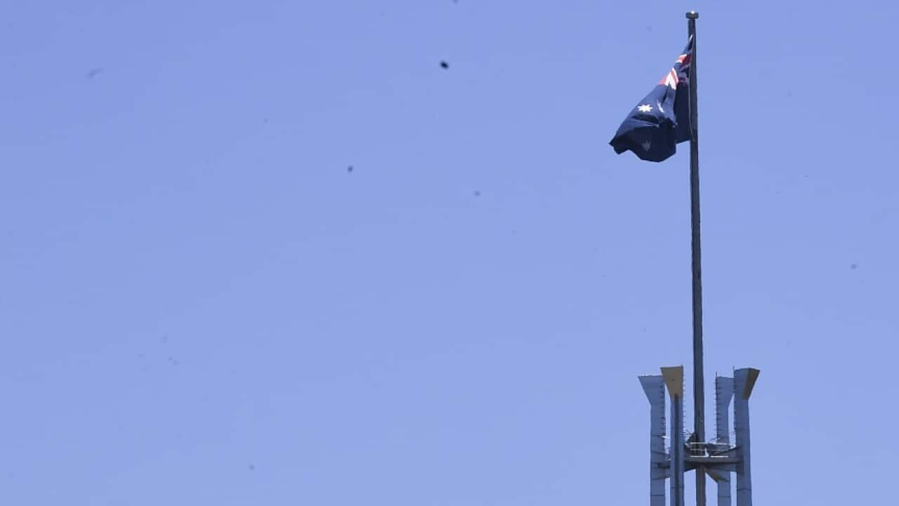 The tower of St Andrews Presbyterian Church is seen near the flag pole of the Australian Parliament House in Canberra, Tuesday, December 21, 2021. (AAP Image/Lukas Coch) NO ARCHIVING