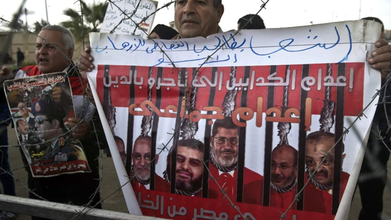 An Egyptian holds a poster behind barbed wires in Cairo
