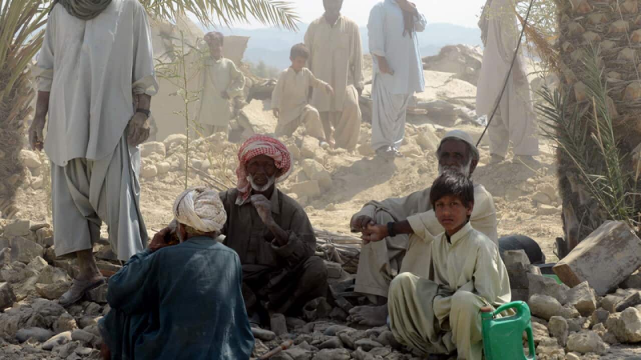 Pakistani earthquake survivors rest near their collapsed mud houses