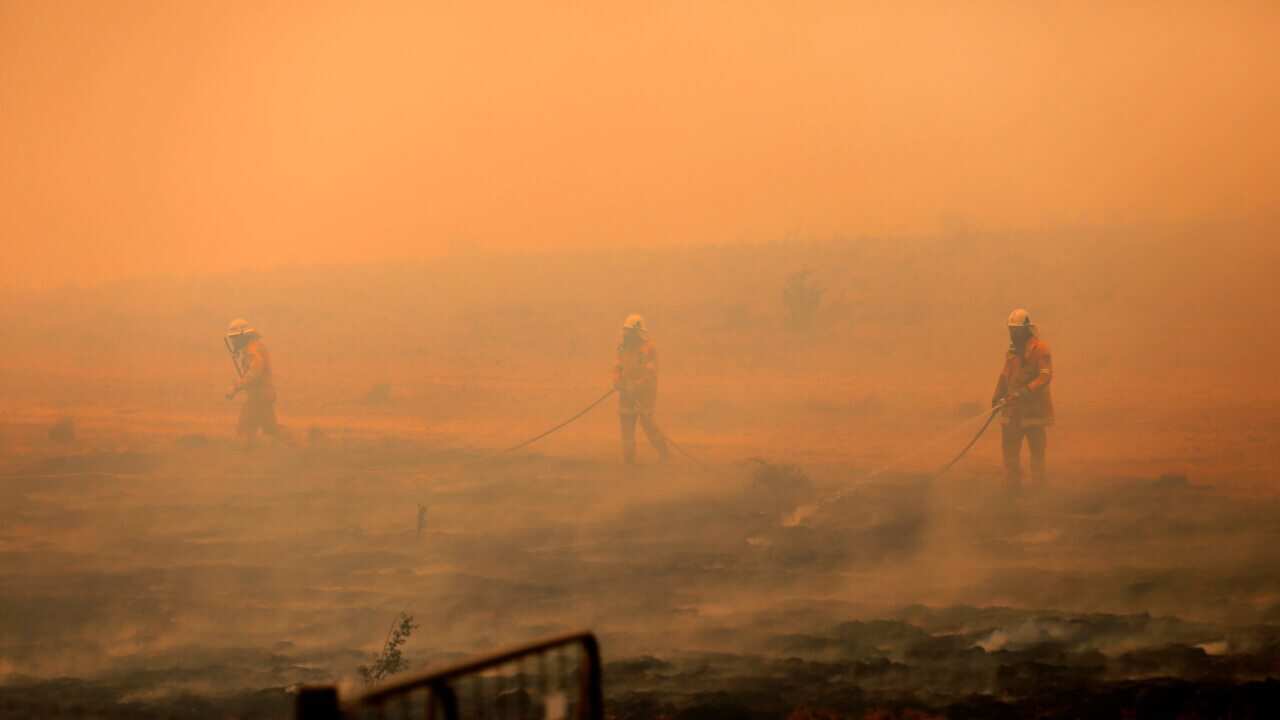 NSW Rural Fire Service crews appear barely distinguishable amid haze after extinguishing a fire that crossed the Monaro Highway, four km north of Bredbo.