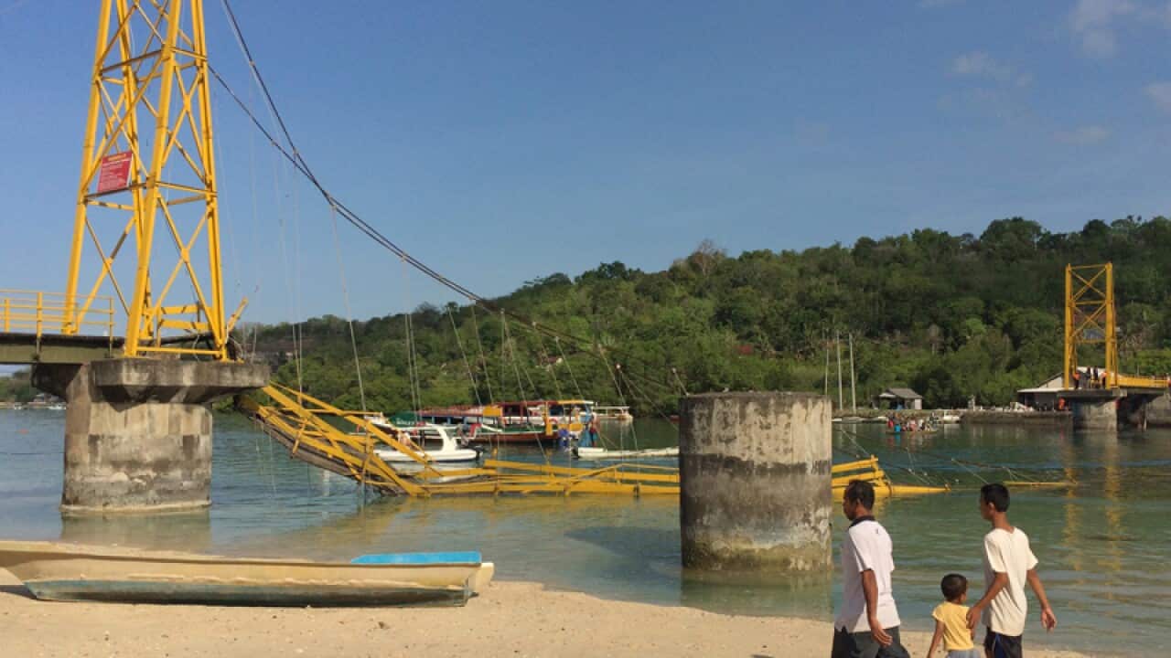 Local people walk by a collapsed bridge near Bali