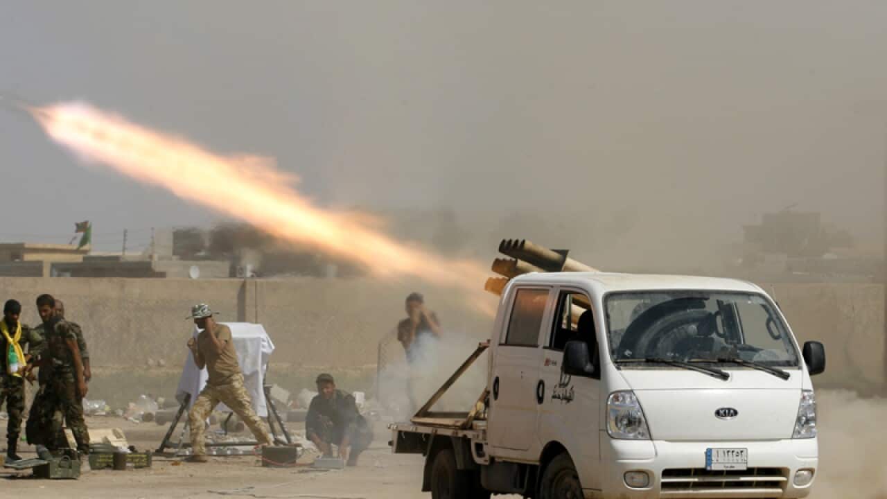 Iraqi security forces fire at IS positions.